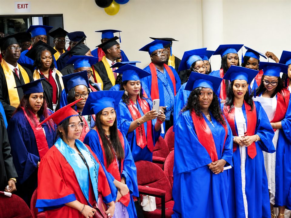 AUOPS graduates wearing blue and red academic gowns